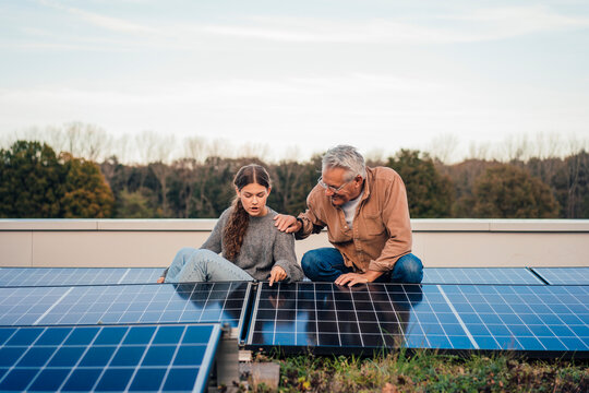 Grandfather and granddaughter discussing solar panels outdoors