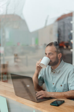 Entrepreneur developer working on laptop and drinking coffee at workspace