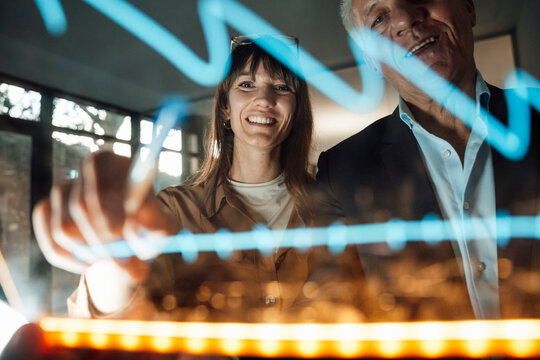 Colleagues in a modern office analyzing digital graph together