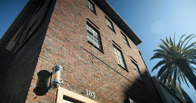 Camera is tilting upward from lower-left, revealing three-story brick facade with barber pole 183