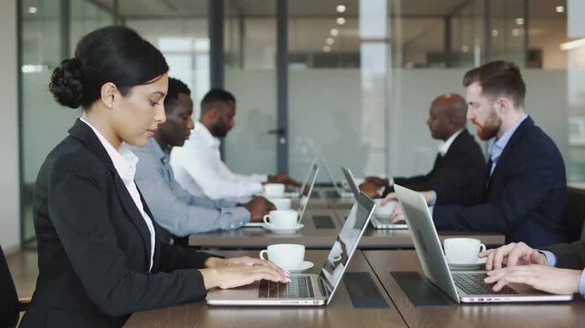 Business minds unite in a sophisticated office space, diligently working on laptops and enjoying warm beverages during a productive workday meeting