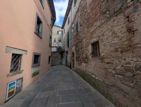 Vicolo storico in pietra con edifici tradizionali e porta ad arco, atmosfera tranquilla di un borgo europeo antico