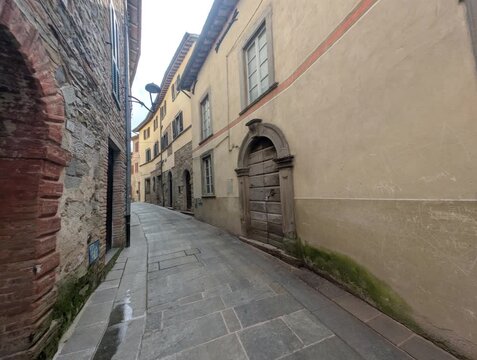 Vicolo storico in pietra con edifici tradizionali e porta ad arco, atmosfera tranquilla di un borgo europeo antico