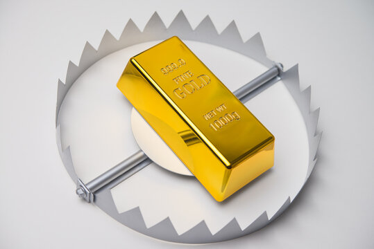 Gold bar in a trap on white background. High risk in commodity trading market all time high price or online scam investment, crime and so on concept.