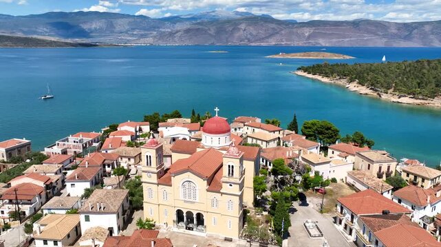 Aerial drone cinematic video from picturesque and traditional historic village of Galaxidi featuring landmark church of Agios Nikolaos, Fokida, Greece