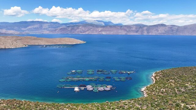 Aerial drone cinematic video of aquaculture fish farm cages producing sea breem and sea bass in deep blue Mediterranean sea