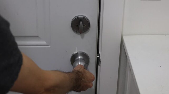 Close-up of a hand firmly holding the door knob after unlocking, ready to open the door completely.