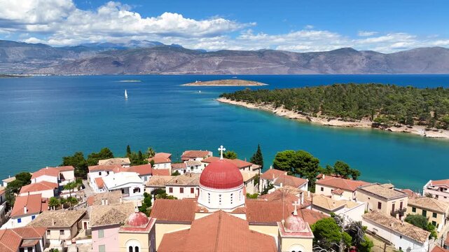 Aerial drone cinematic video from picturesque and traditional historic village of Galaxidi featuring landmark church of Agios Nikolaos, Fokida, Greece