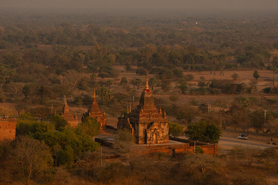 View of ancient temples rising from the arid plains under a hazy sky, a serene yet striking tableau of history and nature, Old Bagan, Mandalay Region, Myanmar.