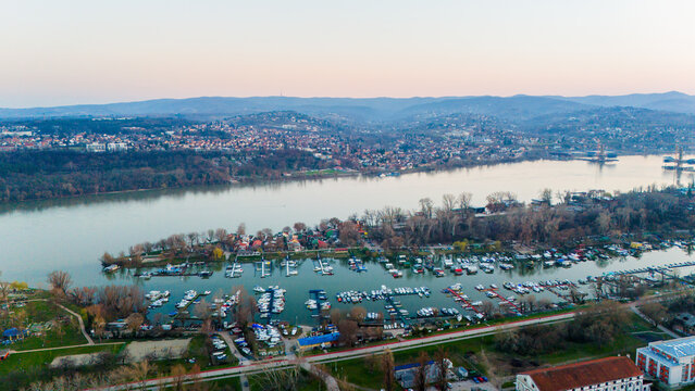 Aerial view of the Danube River reflecting the soft pastel hues of the dusk sky, overlooking a marina filled with boats near the city, Novi Sad, Vojvodina, Serbia.