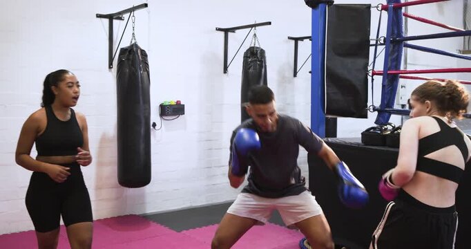 When trainer raising blue gloves inviting sparring on pink mats, teen trainee blocking, countering