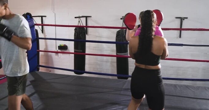 Practicing combos after trainer raising pads, diverse coaches and trainees honing speed at gym