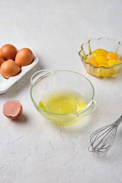 The process of separating eggs into whites and yolks on a white concrete background. Ingredients for cooking.