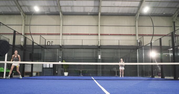 Ball feed machine starting Diverse female athletes rotating on court smashing volleys in practice