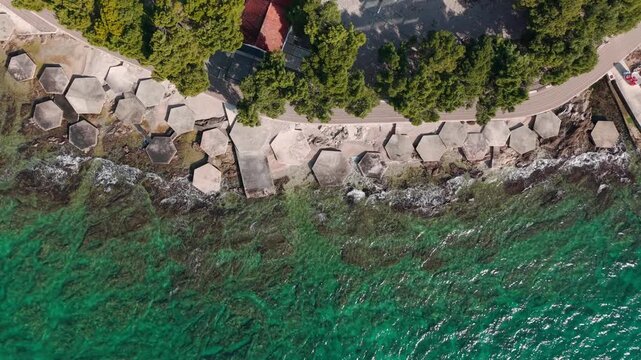 Top-down aerial view of unique hexagonal concrete platforms along rocky coastline at Heksagon beach in Vodice, Croatia, surrounded by clear turquoise Adriatic water and green pine trees
