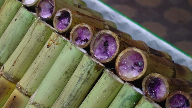 Close-up Pan of Traditional Thai Purple Sticky Rice Bamboo Tubes Khao Lam at Local Street Food Market in Thailand