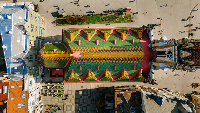 Aerial view of the vibrant, patterned roof of Matthias Church, a tapestry of green, yellow, and red, standing proudly, Sad, Vojvodina, Serbia.