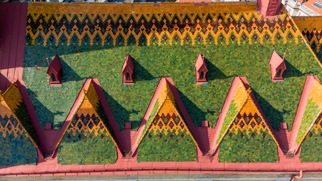 Aerial view of a rooftop adorned with vibrant green, yellow, and red tiles in a geometric pattern, Sad, Serbia.