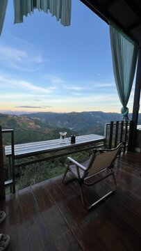 Coffee drip set on a wooden balcony overlooking a mountain valley at twilight.