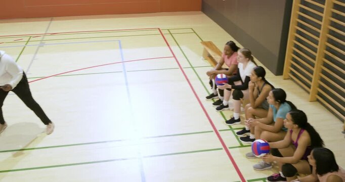 African American coach starting drill with tablet female players holding tricolor balls, copy space