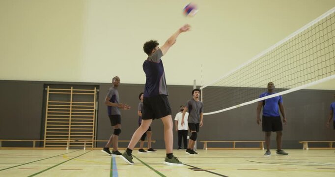 After far-side toss, African-American man passing ball to return rally in gym near net, copy space