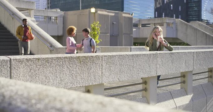 Blonde woman rail talking phone holding cup, pink-top coming bag man meeting at stairs, copy space
