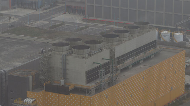 Aerial view of cooling towers rise above a sprawling industrial complex, a symphony of concrete and steel against the hazy sky, Changhua, Taiwan.
