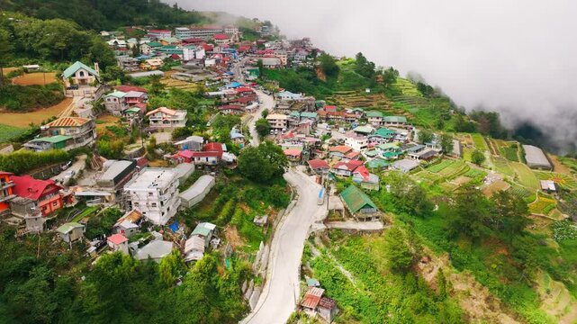 Cinematic drone flight above mountain village and winding road Atok Benguet