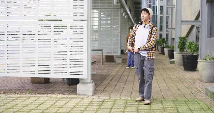 Diverse male students noticing friend approaching campus, checking phone, greeting, sharing notes