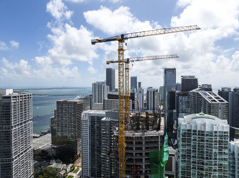 Aerial view of towering cranes puncturing the skyline amidst a sea of high-rise buildings, capturing the essence of urban development in Brickell, Miami, Florida, United States.