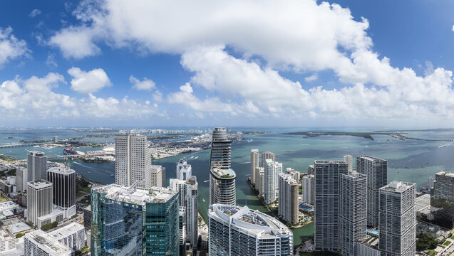 Aerial view of modern skyscrapers pierce the skyline, reflecting the sun's light with the ocean's shimmer in the distance, Brickell, Miami, Florida, United States.