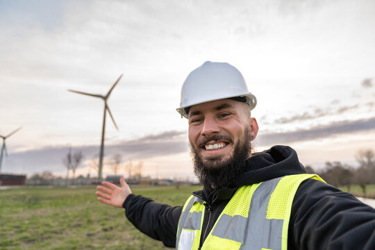 Renewable energy engineer smiling taking a selfie at a wind farm, highlighting sustainable power and green technology