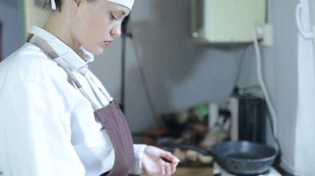 A female chef cooks in the kitchen at home wearing a chef's costume