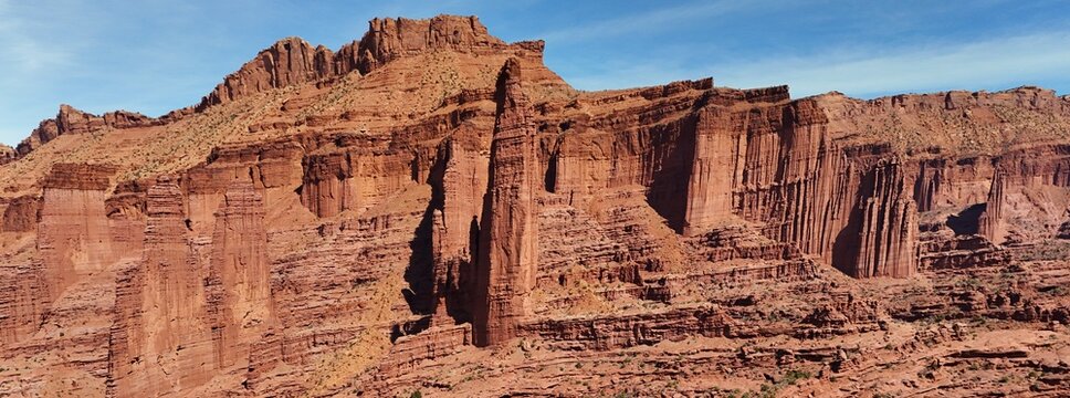 Aerial view of the majestic red rock formations, carved by time and weather, stand tall against the clear blue sky, Moab, Utah, United States.