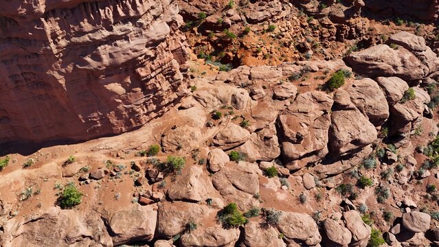 Aerial view of the rugged, sun-baked landscape reveals a tapestry of terracotta hues and jagged contours, etched by time and elements, Moab, Utah, United States.
