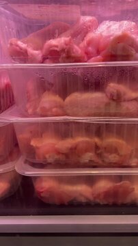 Fresh chicken meat packaged in plastic containers displayed on store shelves, highlighting retail food sales and supermarket assortment. Vertical video taken on mobile device as UGC.