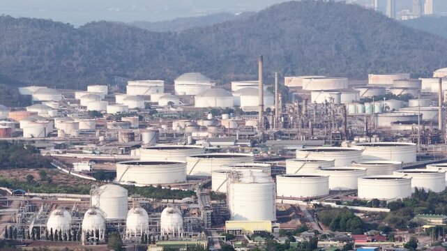 High angle view showing large white and rusty storage tanks at a massive crude oil refinery and petrochemical plant, representing the global fossil fuel industry and energy production