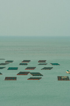 Aerial View of Rectangular Fish Farming Platforms and Small Boat on Calm Sea