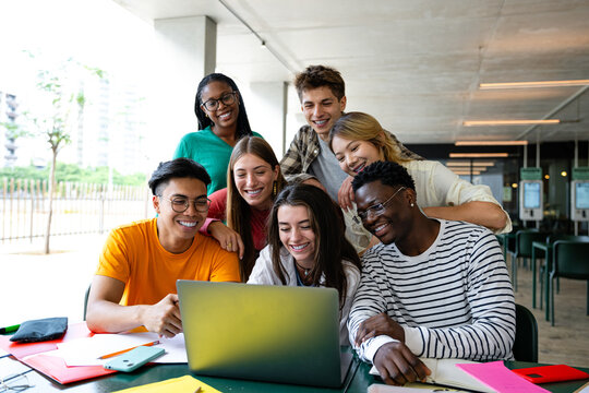 Diverse students collaborate enthusiastically on a laptop in a modern creative study space