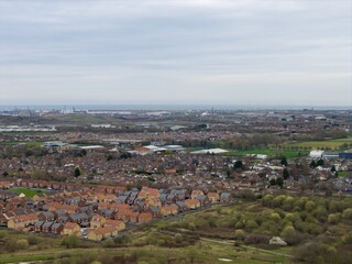 Fototapeta premium Aerial view of the Middlesbrough housing and industrial port area with wind turbines and coastline showing contrast between residential streets and heavy industry in the daytime in early spring