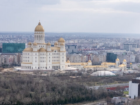 Aerial view of a majestic white and gold cathedral piercing the skyline above a dense city sprawl, Bucharest, Bucuresti, Romania.