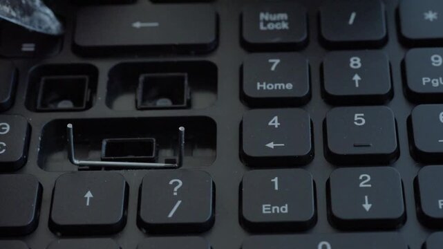Cinematic keyboard teardown under colored light showing multiple missing keys and exposed stabilizers, tool moving across numpad area, empty sockets and beginning of cleanup,