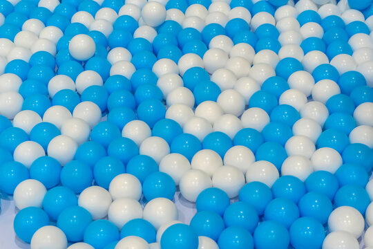 A background texture of many blue and white plastic balls in a ball pit playground.