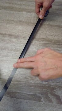 Aligning and removing air from tape on laminated flooring surface. Ensuring proper tape placement and bubble elimination for neat cable routing on laminate surfaces