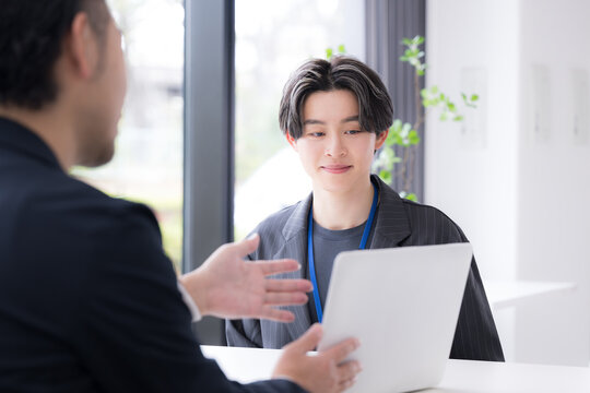 仕事での面談やキャリアカウンセリングなど対面で面接する爽やかなビジネスイメージ　デザイナーやエンジニア、マーケターなどクリエイティブ職のインターンなど新卒の若い男性