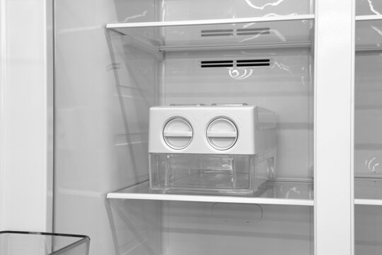 White plastic automatic ice maker appliance unit inside spacious modern refrigerator freezer