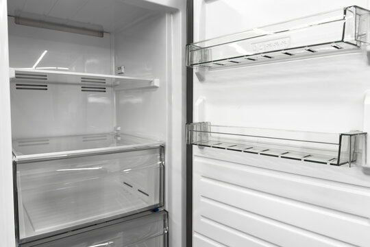 Inside a modern household cooling appliance with empty clear plastic storage shelves and drawers