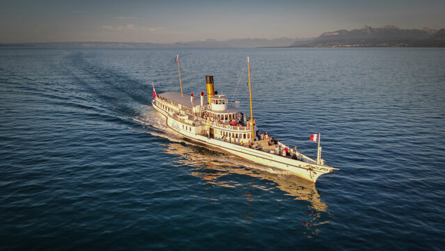 Yvoire, France - 07 July 2023: Aerial view of a vintage steamboat cutting through the tranquil, sun-kissed waters, a dance of light and shadow on its elegant form.