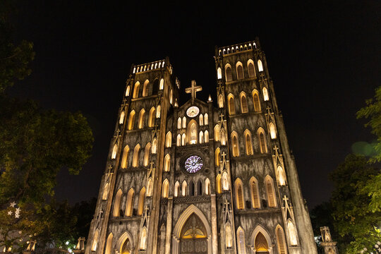 View of St. Joseph's Cathedral, a neo-Gothic masterpiece, glows with warm light against the inky Hanoi night sky, its spires reaching for the heavens, Hanoi, Ha Noi, Vietnam.
