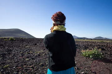 Obraz premium A woman seen from behind, in a half-length shot, as she is on the phone and looking out towards the horizon.